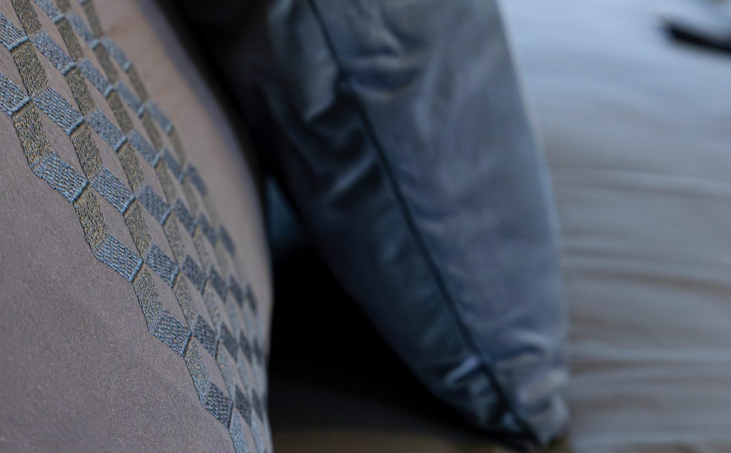 Détail textile d’un fauteuil et de coussins bleus, révélant le soin porté aux matières et au confort au Clos Cathala